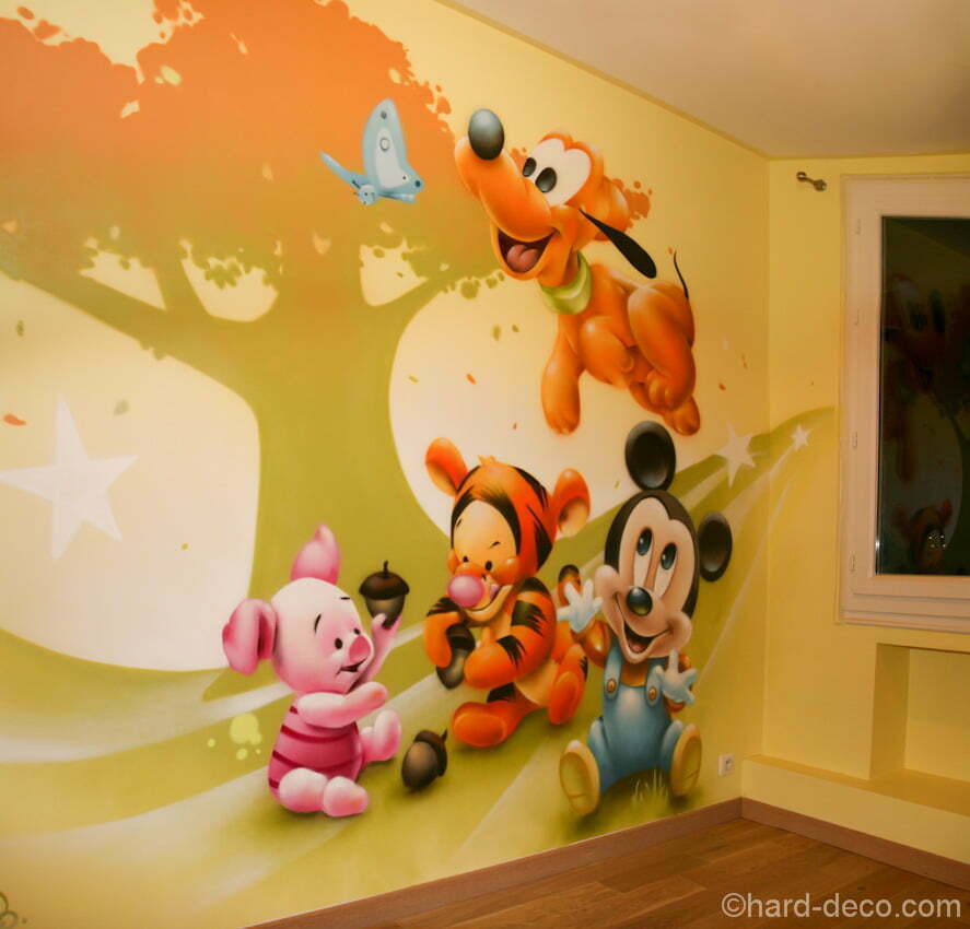 Quatre des personnages Disney sur fond graphique sur un mur d'une chambre de bébé