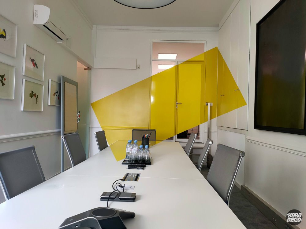 Salle de réunion avec anamorphose jaune sur fond blanc, table blanche et chaises grises, Paris 17e