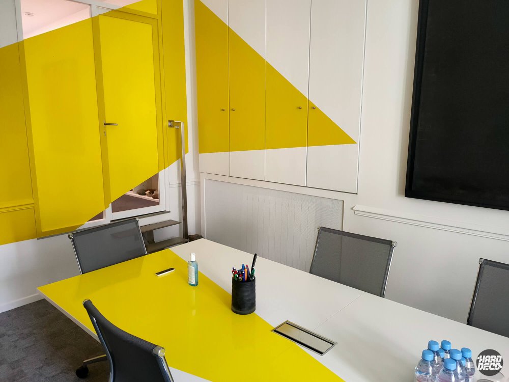 Anamorphose géométrique jaune sur mur et porte d'une salle de réunion, bureaux Paris 17e