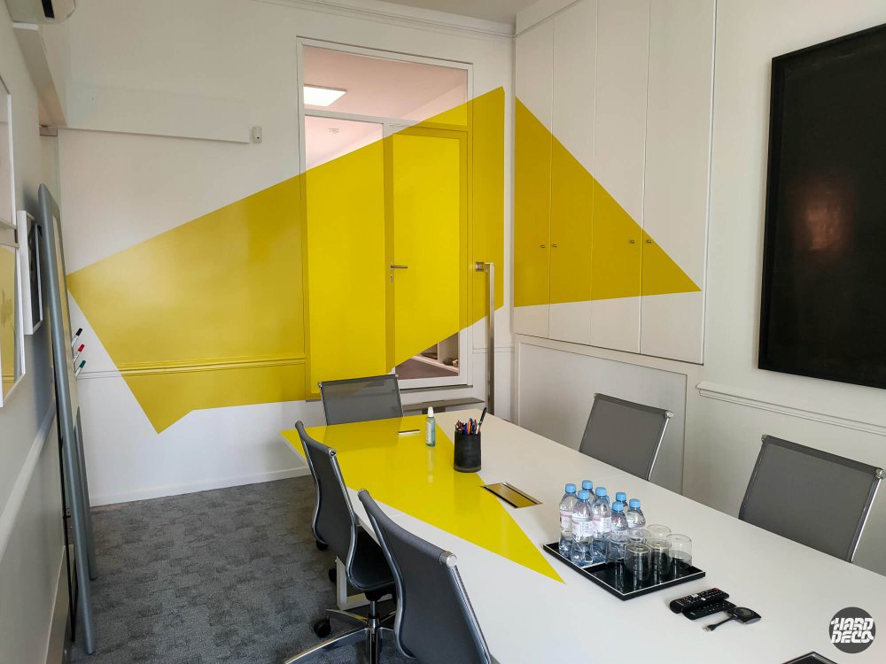 Anamorphose jaune déployée sur toute la largeur du mur fond, salle de réunion bureaux Paris