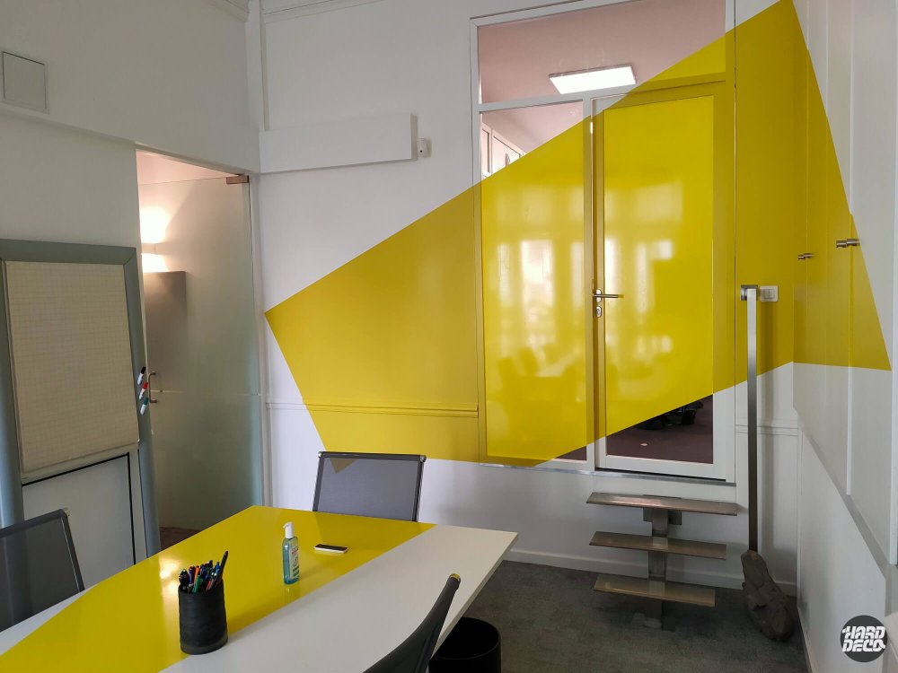 Forme géométrique jaune en anamorphose couvrant mur et porte laquée, bureaux Diderot Real Estate Paris
