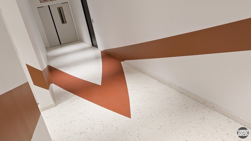 Anamorphose sol et mur couloir Warner Issy-les-Moulineaux, chevron terracotta traversant l'angle bas