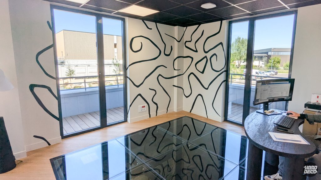 Décor mural abstrait noir et blanc dans un bureau vitré avec reflet dans le sol en verre poli