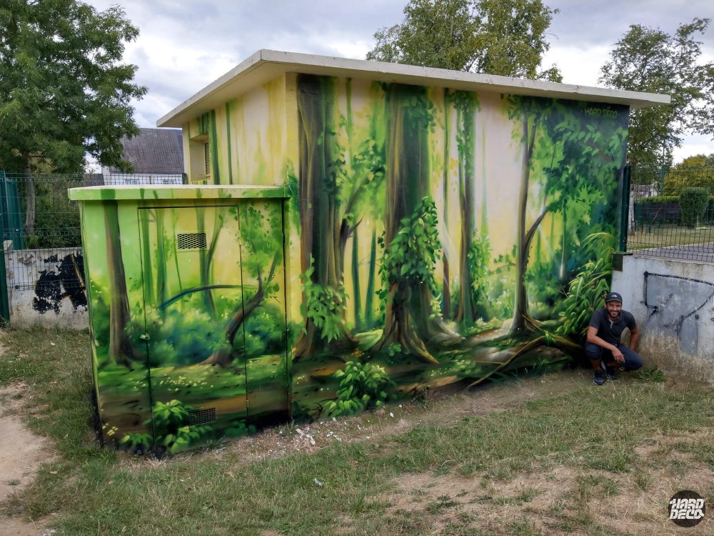 Fresque aérosol forêt tempérée sur local EDF, vue perspective avec artiste en pied, racines et sous-bois lumineux