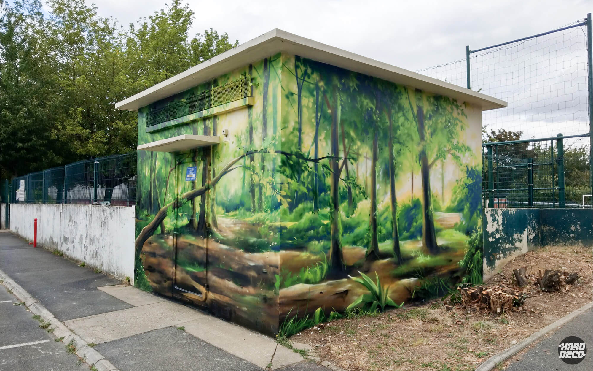 Fresque aérosol forêt tempérée sur transformateur EDF, vue d'angle sur deux faces, tronc couché au premier plan