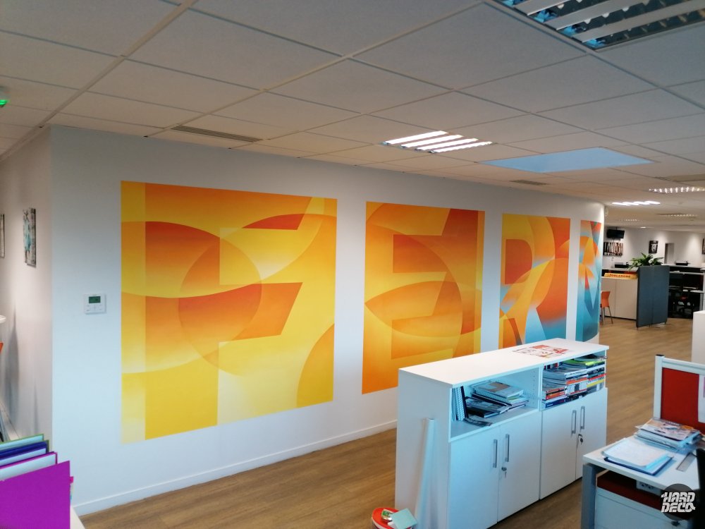 Détail des toiles aérosol orange et jaune avec formes géométriques abstraites dans l'open space Cogeferm