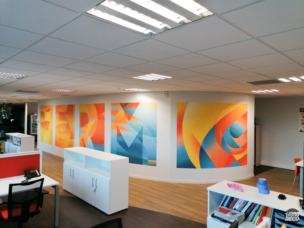 Vue large de l'open space Cogeferm avec toiles aérosol colorées orange bleu et jaune sur mur arrondi