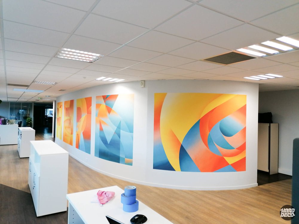 Panoramique des toiles murales aérosol Cogeferm déployées sur mur incurvé en orange bleu et jaune