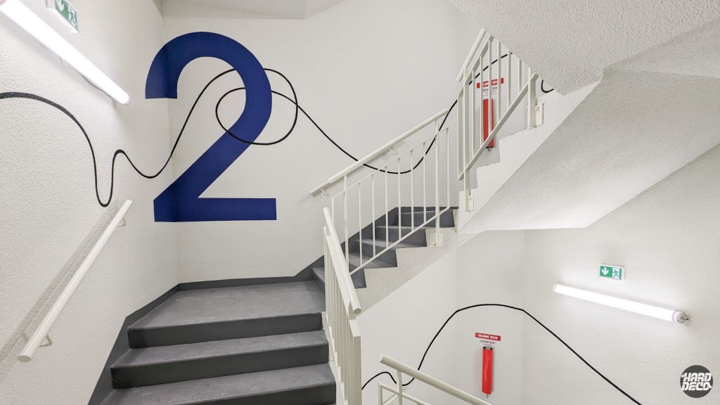 Palier du 2e étage, chiffre bleu cobalt encerclé par un fil noir aérosol, décor mural cage d'escalier entreprise