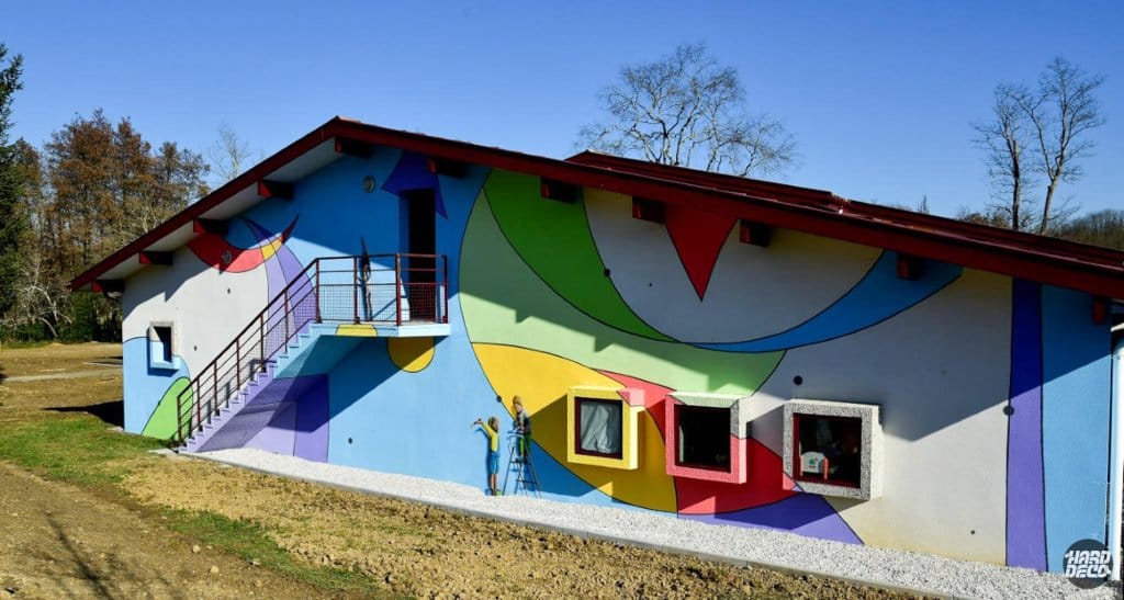 Fresque géométrique colorée inspirée de Miró sur la façade de l'école maternelle de Pouillon, vue de face