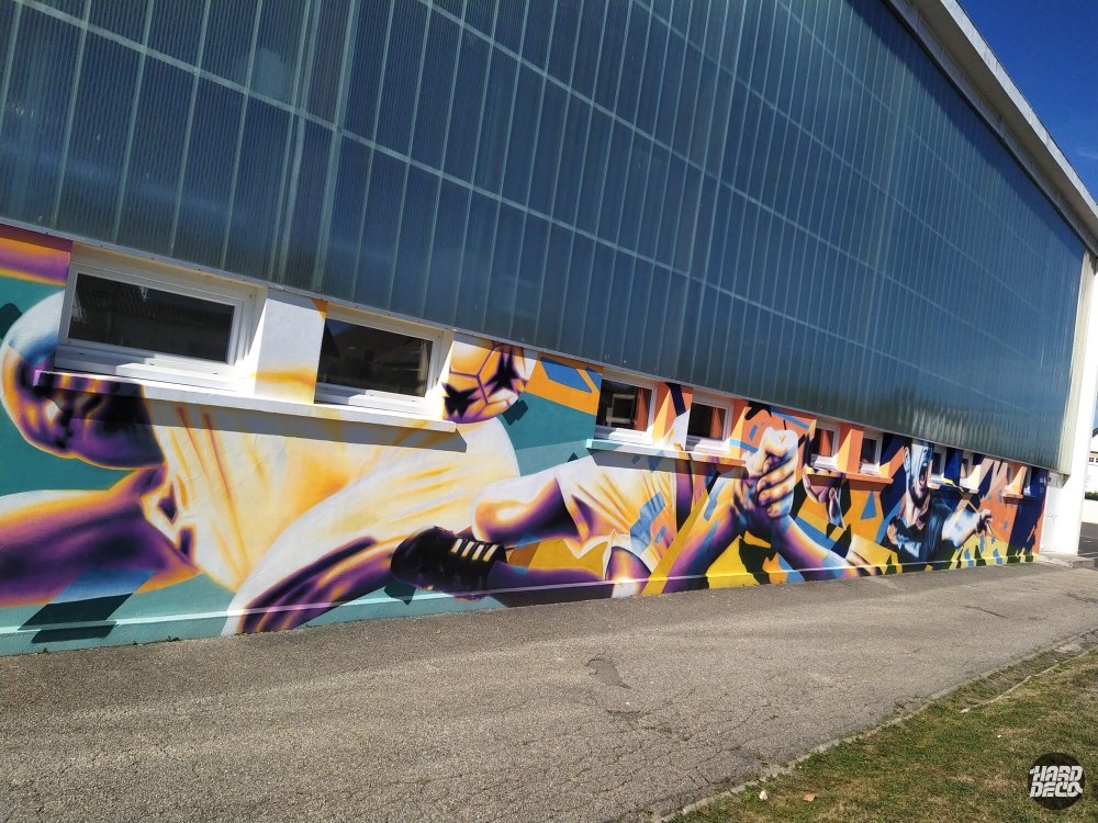 Fresque murale gymnase Pontault-Combault, footballeur en extension jaune violet, façade extérieure aérosol