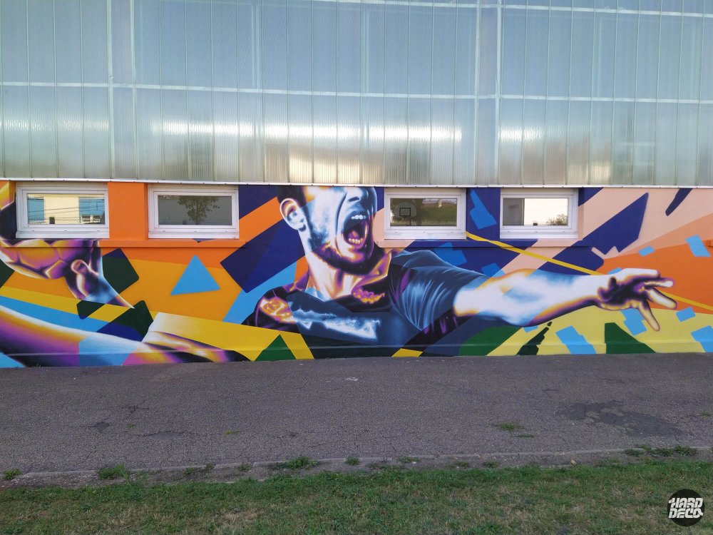 Fresque aérosol gymnase Pontault-Combault, portrait sportif bras tendus sur fond géométrique violet orange