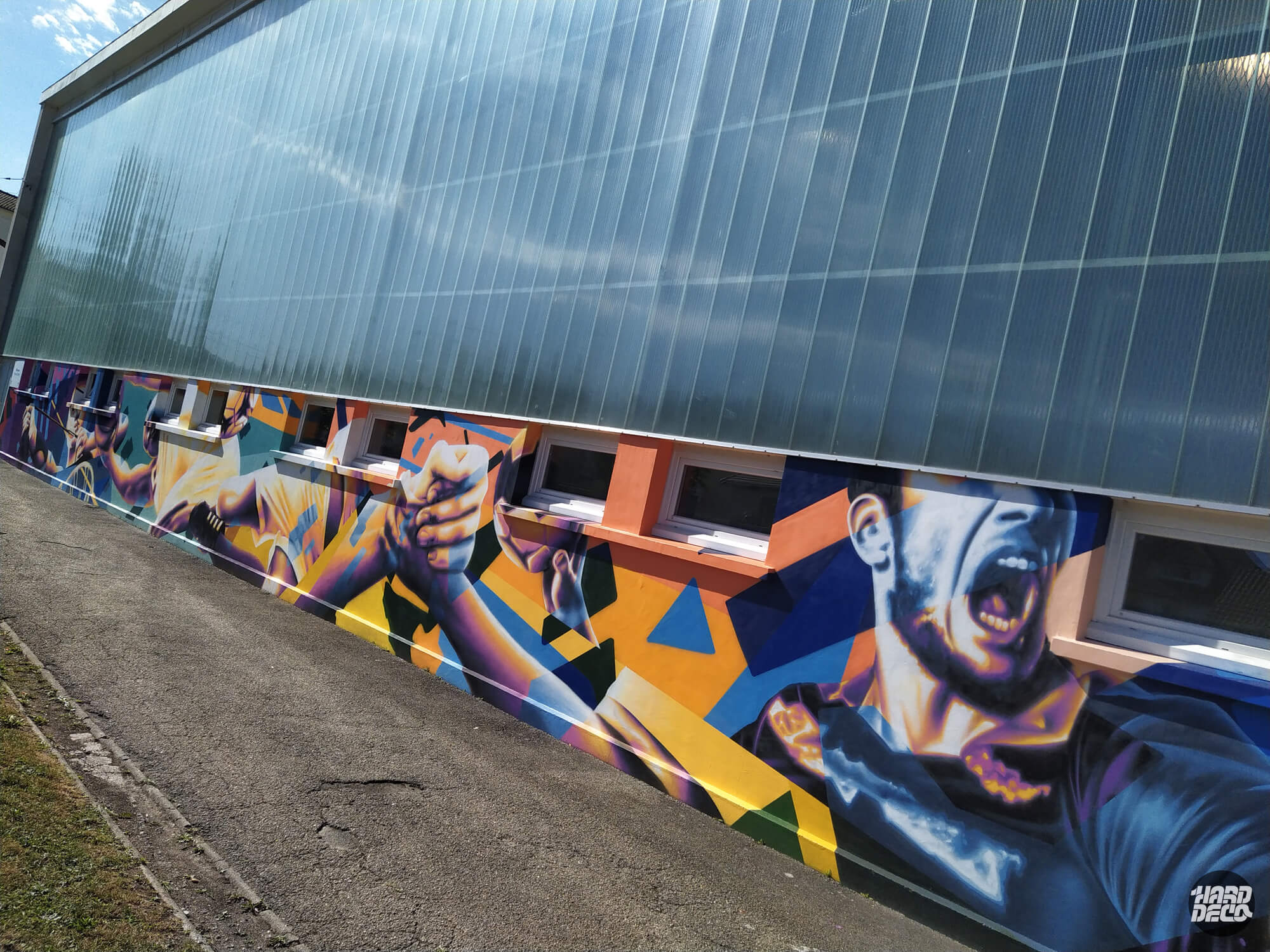 Fresque aérosol façade gymnase Pontault-Combault, joueur de sport et formes géométriques orange et bleu