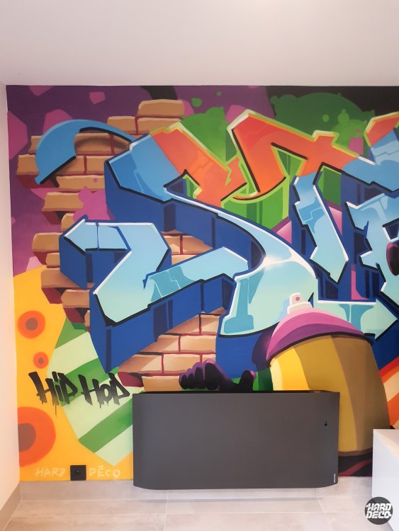 Détail fresque graffiti hip-hop salon, lettres bleues sur mur de briques, inscription Hip Hop et bombe rose
