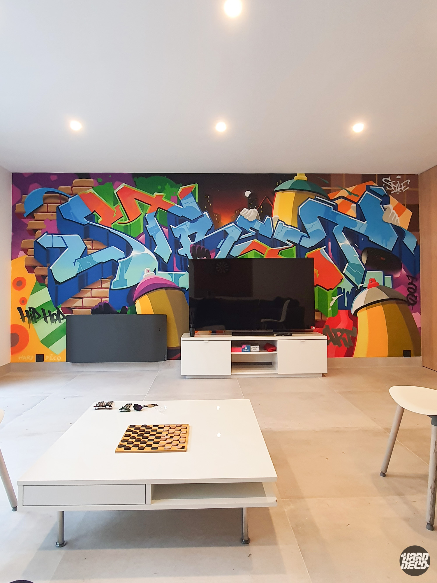Fresque graffiti hip-hop dans un salon particulier, lettres bleues et bombes aérosol, vue d'ensemble avec table basse
