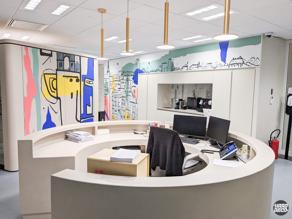 Accueil circulaire bureaux Kantar Bagneux avec fresques murales skyline parisien et figure graphique