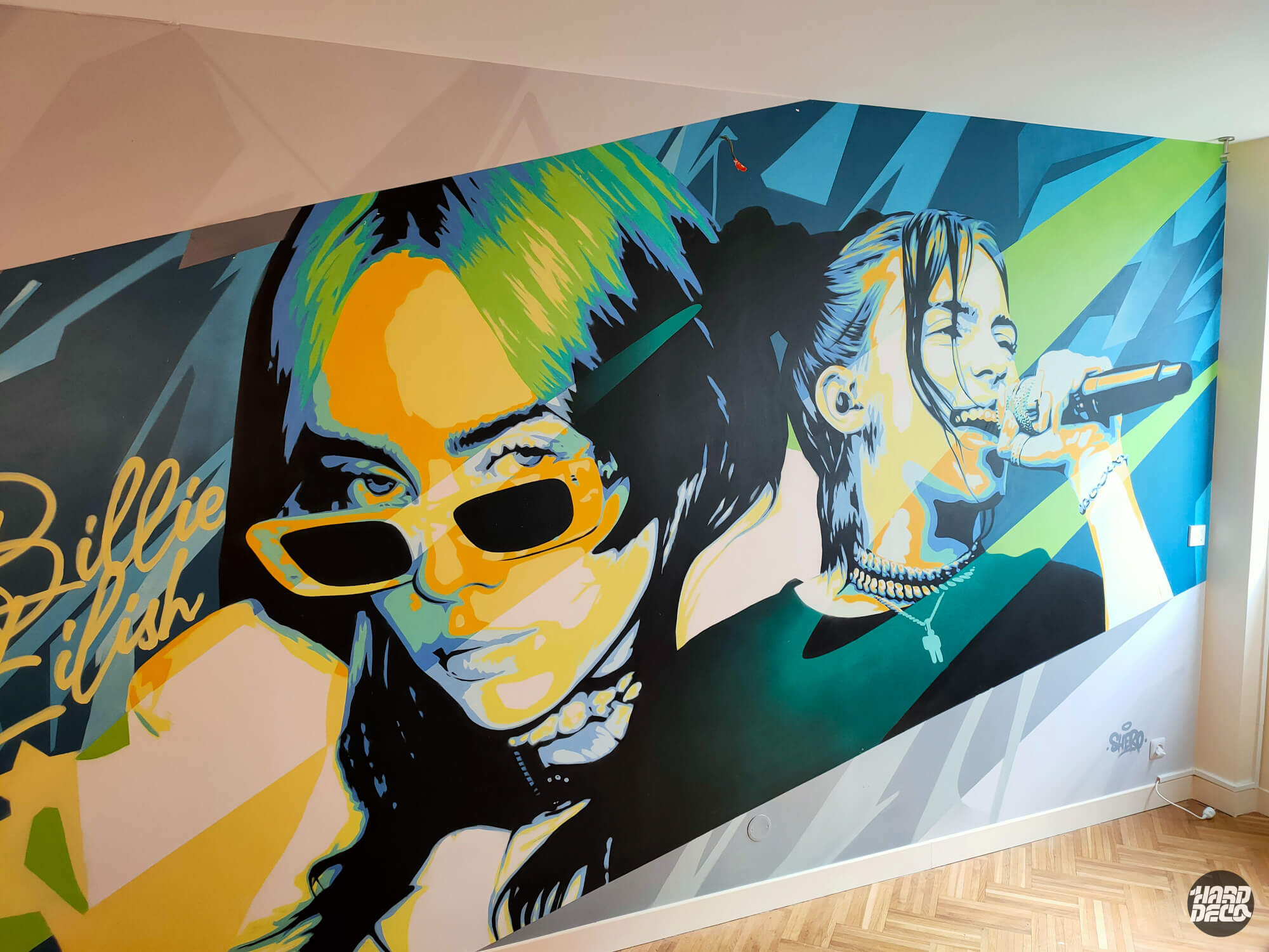 Fresque Billie Eilish aérosol en chambre, double portrait pop art sur fond géométrique bleu et vert, gros plan