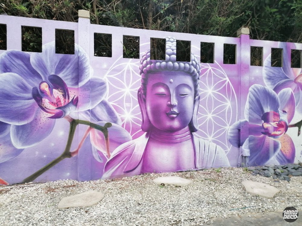 Détail du visage de Bouddha en violet avec motif géométrique fleur de vie sur fresque extérieure