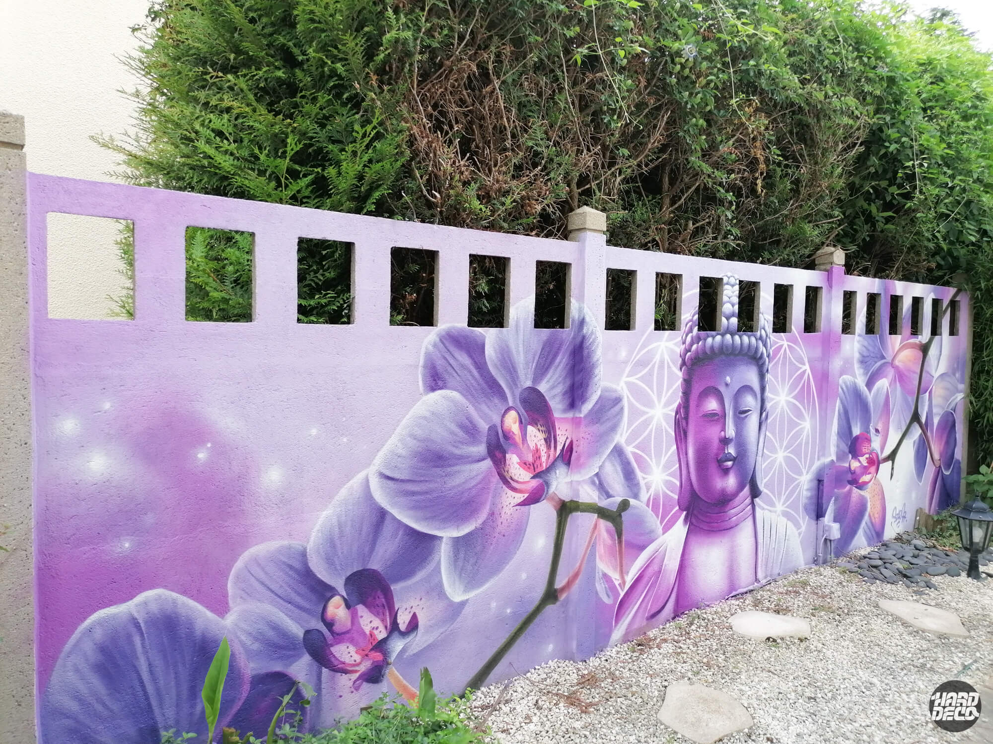 Fresque murale aérosol Bouddha et orchidées violettes sur clôture de jardin, vue d'ensemble
