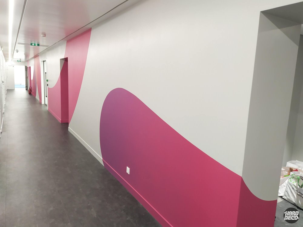 Fresque murale abstraite rose et mauve foncé sur couloir d'entreprise TCS, formes organiques arrondies