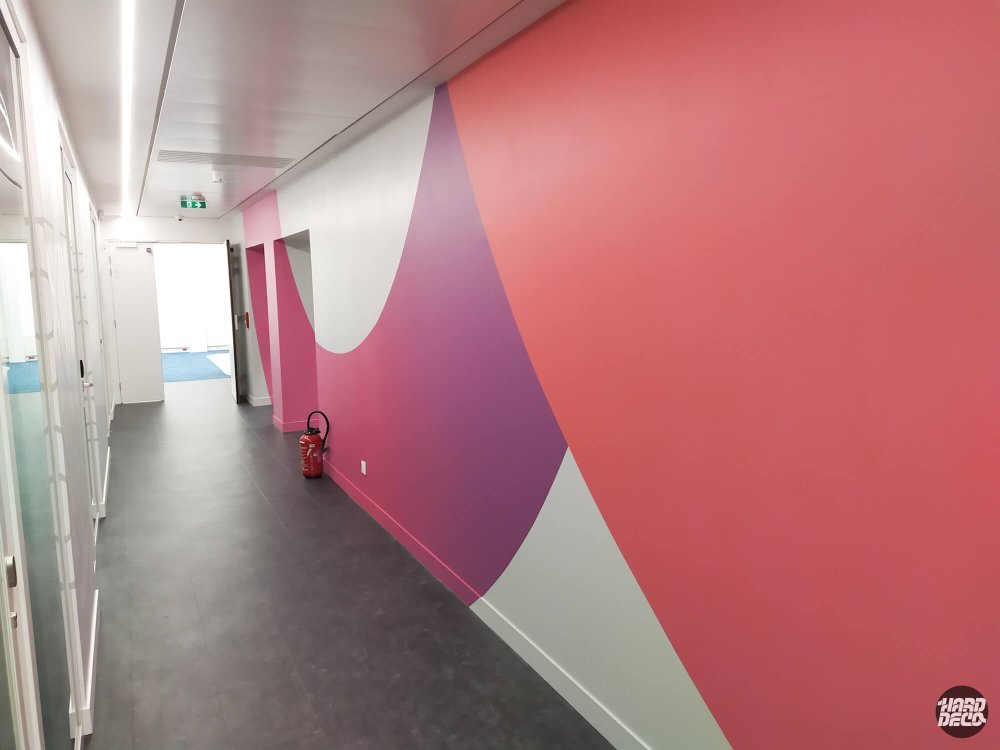 Fresque abstraite couloir TCS avec aplats rose saumon et violet prune sur mur placo, vue latérale