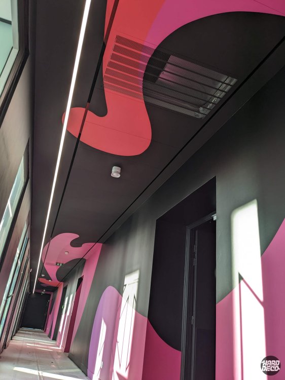 Plafond et mur peints en noir et fuchsia avec formes abstraites organiques dans couloir de bureaux TCS