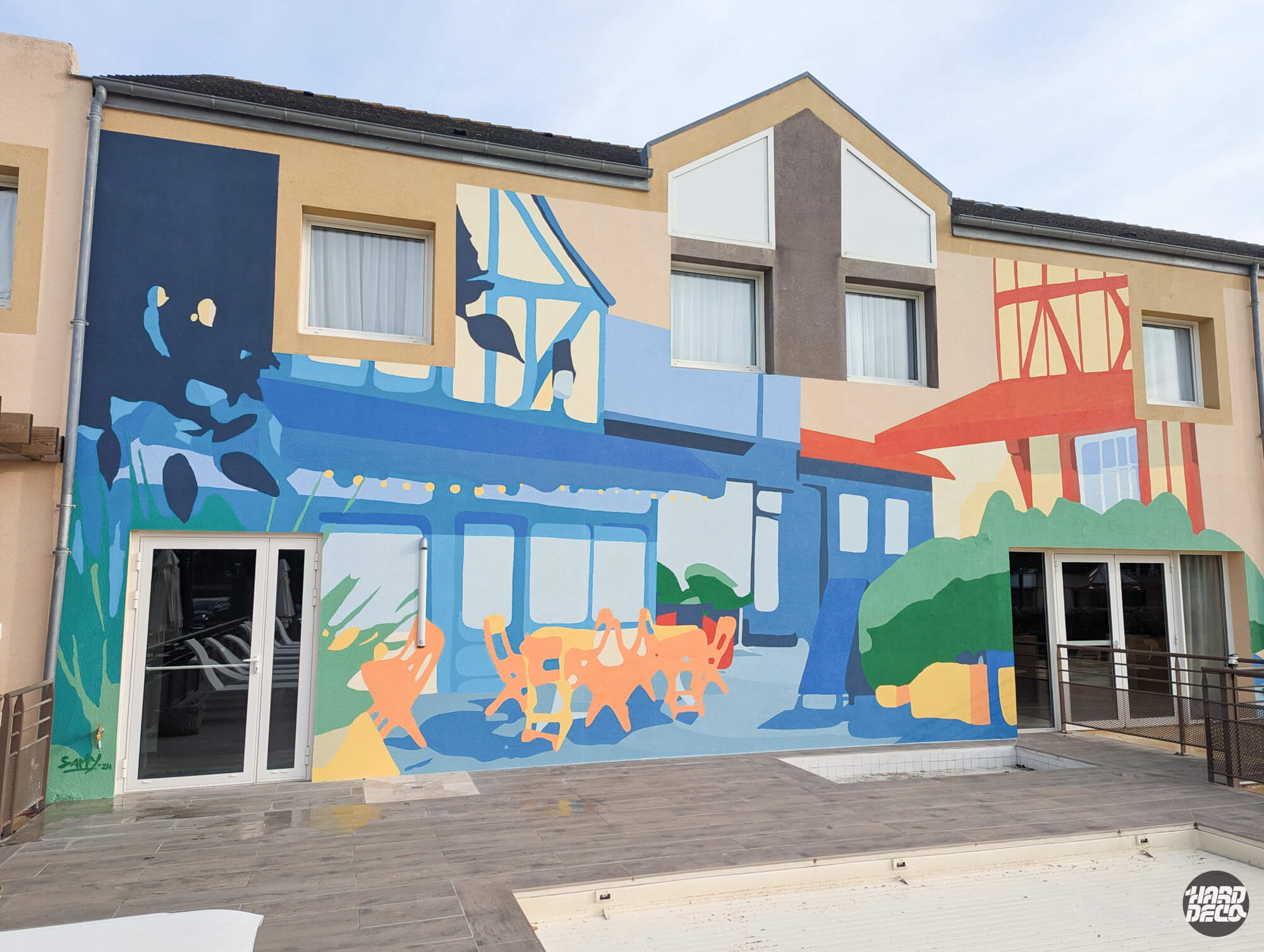 Fresque murale terminée sur façade hôtel à Caen, scène normande en à-plats bleus ocres et verts