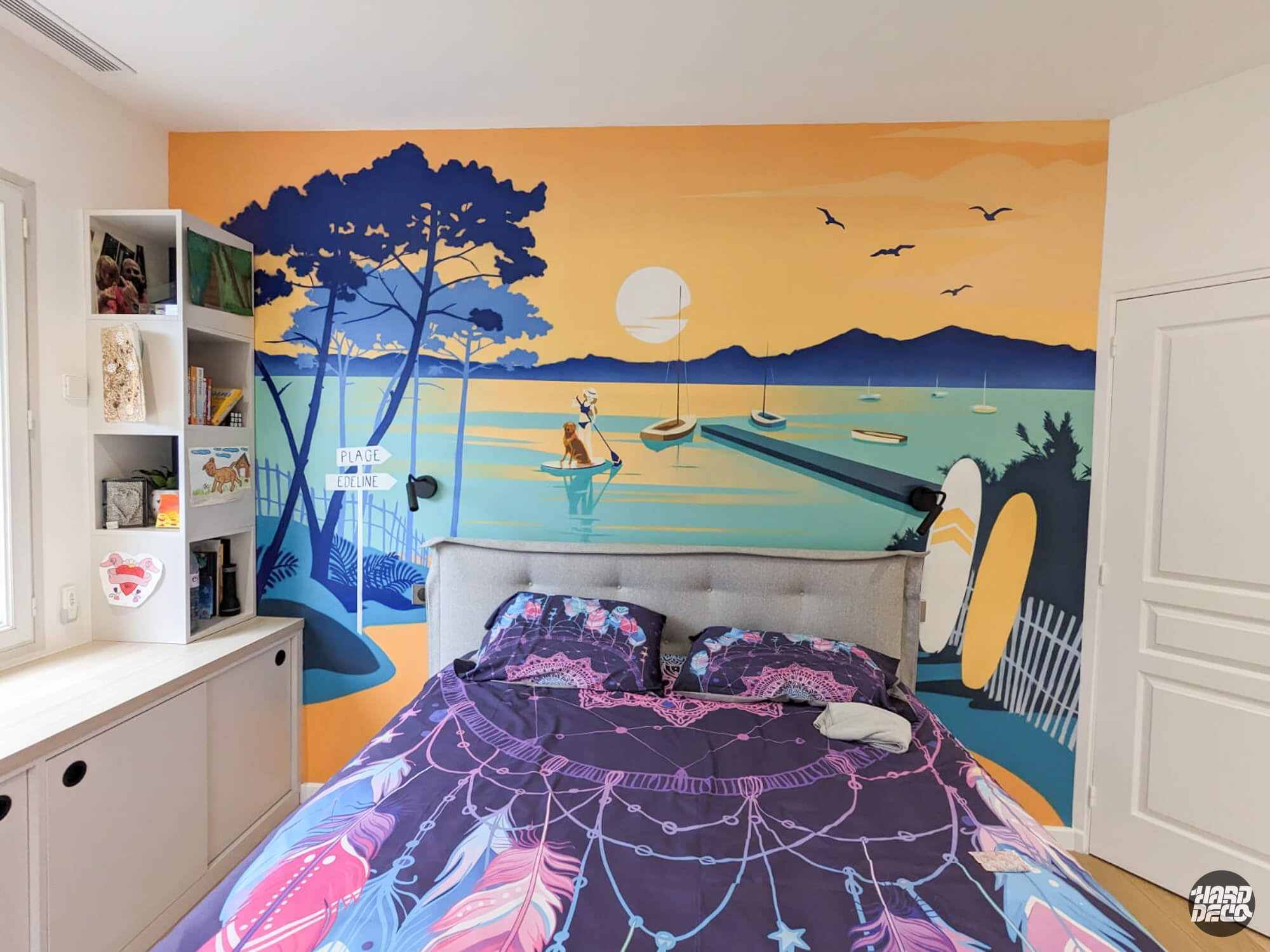 Fresque murale bord de mer style affiche vintage dans une chambre d'adolescente, coucher de soleil orange et bleu