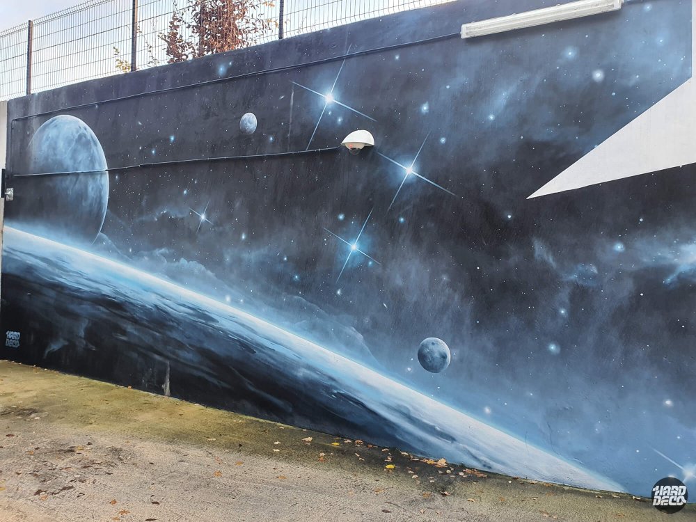 Fresque murale spatiale à l'aérosol : planète, lune et étoiles sur fond bleu nuit, parking Celeste Champs-sur-Marne