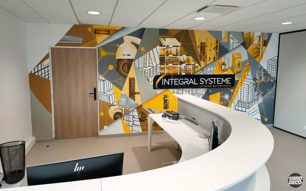 Fresque aérosol jaune et gris Integral Systeme avec caméras et logo, vue depuis le comptoir d'accueil