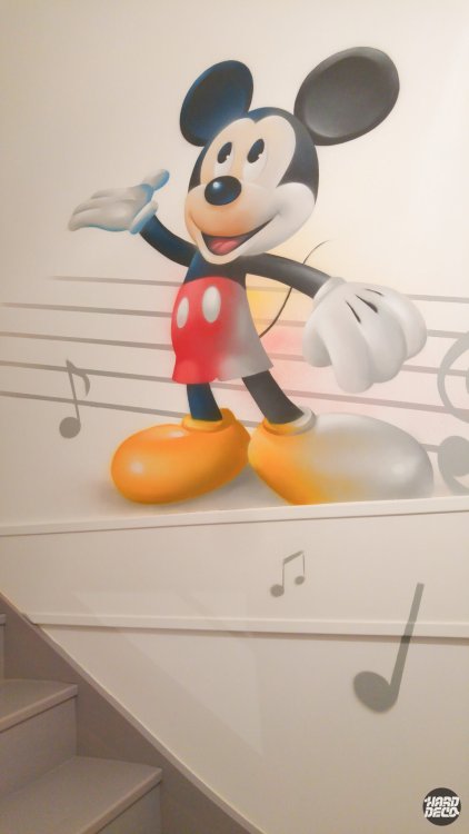 Mickey Mouse coloré en rouge et jaune peint à l'aérosol sur mur d'escalier avec notes de musique grises