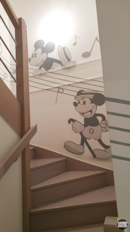 Fresque escalier Mickey Mouse style années 1920 noir et blanc avec portées musicales sur deux niveaux