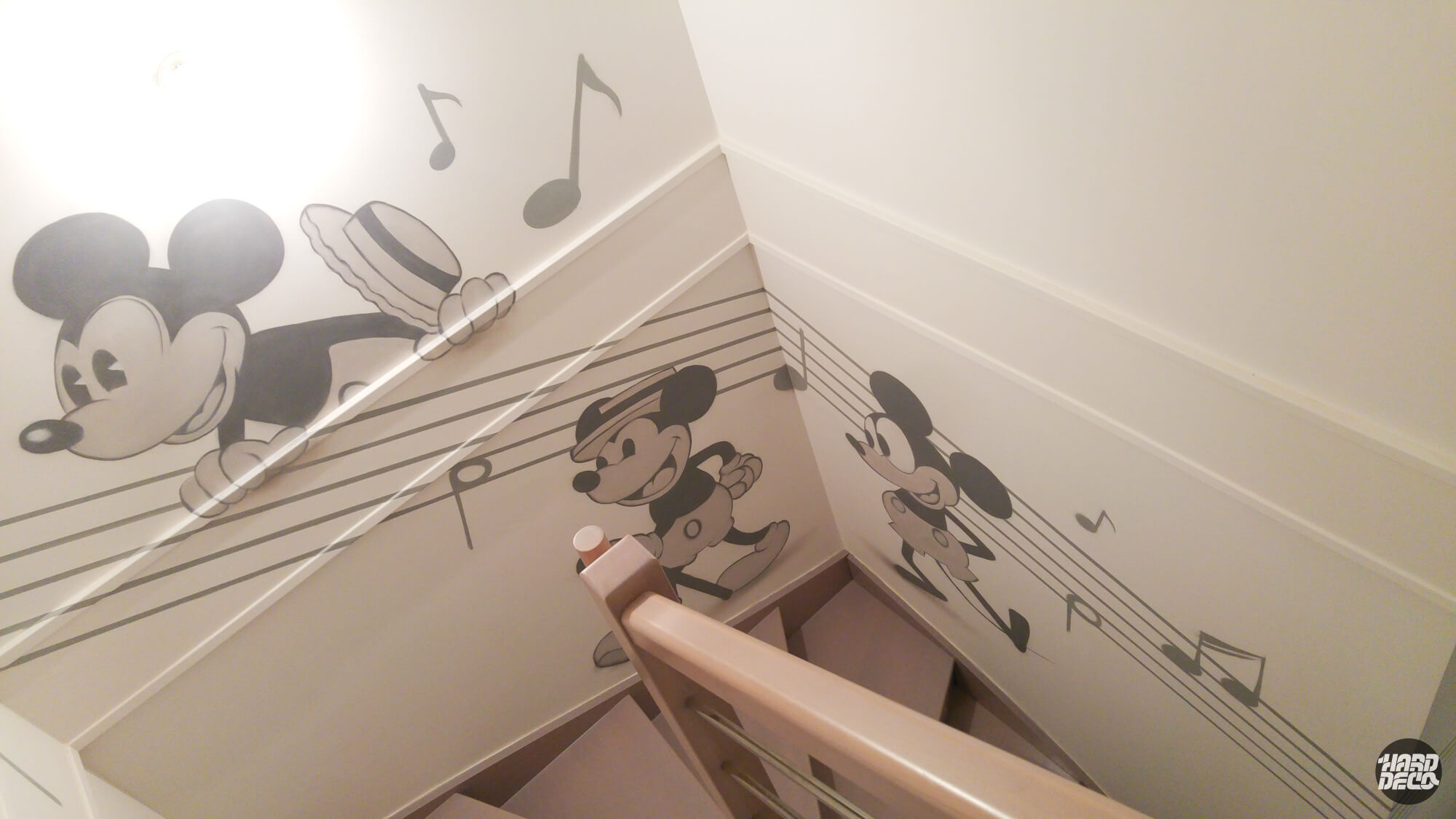 Fresque murale Mickey Mouse vintage noir et blanc dans un escalier avec portées et notes de musique