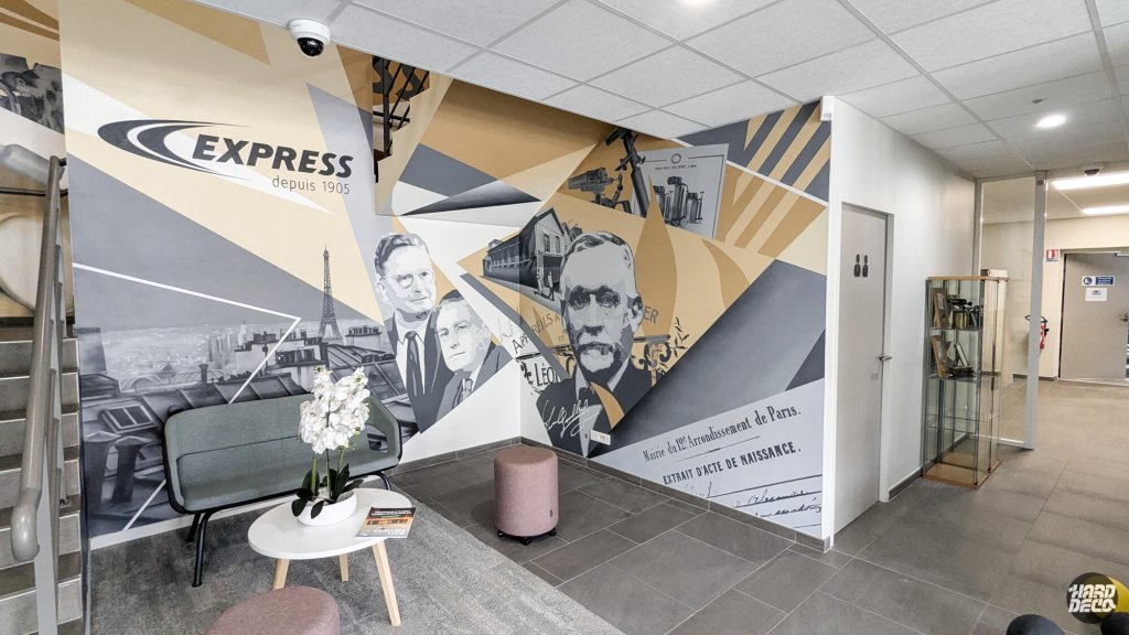 Fresque murale Express 120 ans dans le hall d'accueil, portraits en grisaille et géométrie dorée