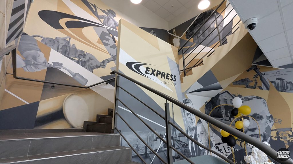 Vue escalier fresque Express deux niveaux, logo et portraits fondateurs sur composition angulaire dorée