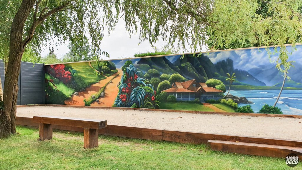 Fresque murale extérieure paysage polynésien sur clôture de jardin, vue d'ensemble boulodrome