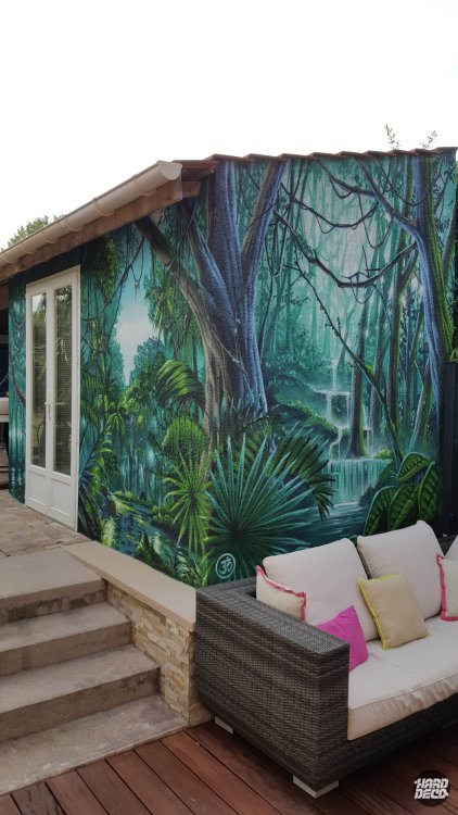 Fresque murale jungle aérosol sur façade extérieure avec cascade, lianes et palmiers, vue d'ensemble