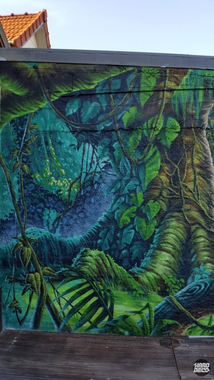 Détail fresque jungle, sous-bois bleu-vert profond avec lianes, fougères et feuillages tropicaux peints à l'aérosol