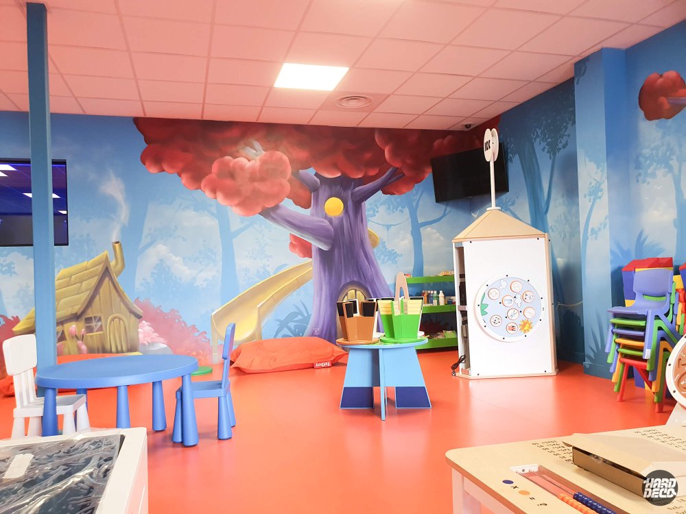 Fresque murale forêt enchantée salle de jeux Fitness Park, arbre violet et maisonnette de chaume peints à l'aérosol