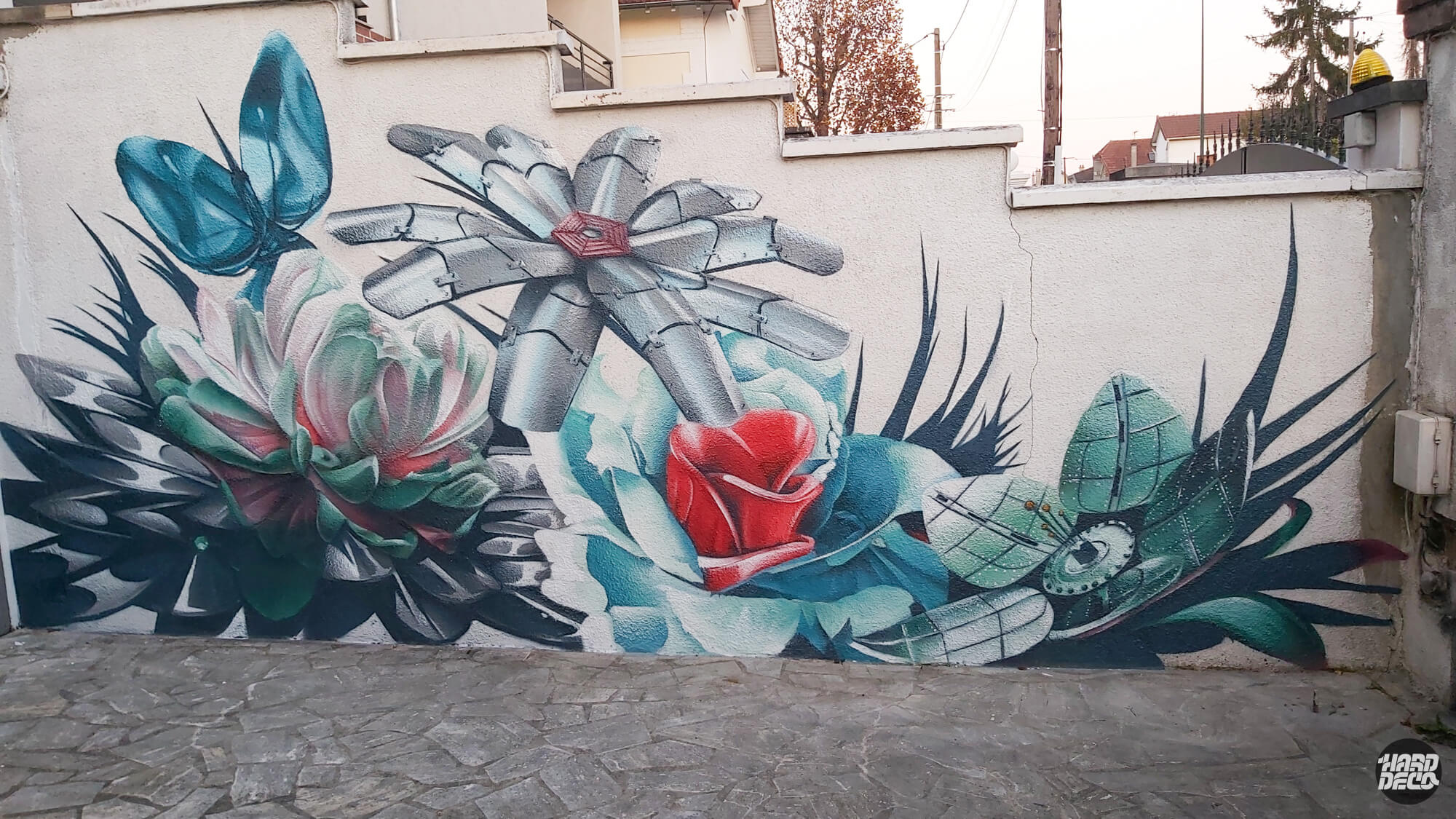 Fresque murale extérieure fleurs mécaniques, libellule en acier et papillon cybernétique, palette bleu et rouge à l'aérosol