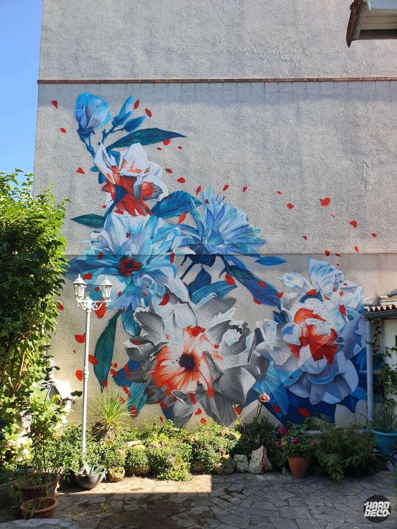 Fresque murale florale 36 m² sur façade de jardin privé, composition diagonale bleu cobalt, gris et orange à l'aérosol, vue ensemble
