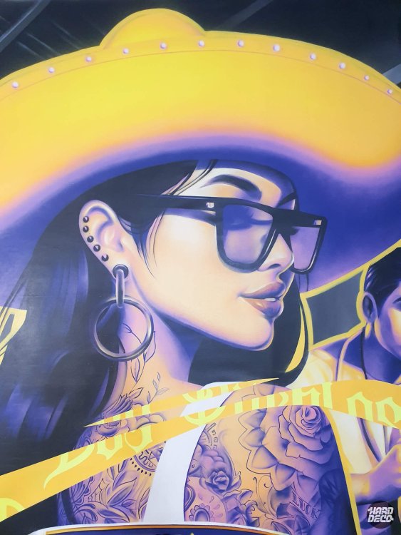 Gros plan portrait femme au sombrero jaune et tatouages floraux, fresque aérosol Los Pueblos Grenoble