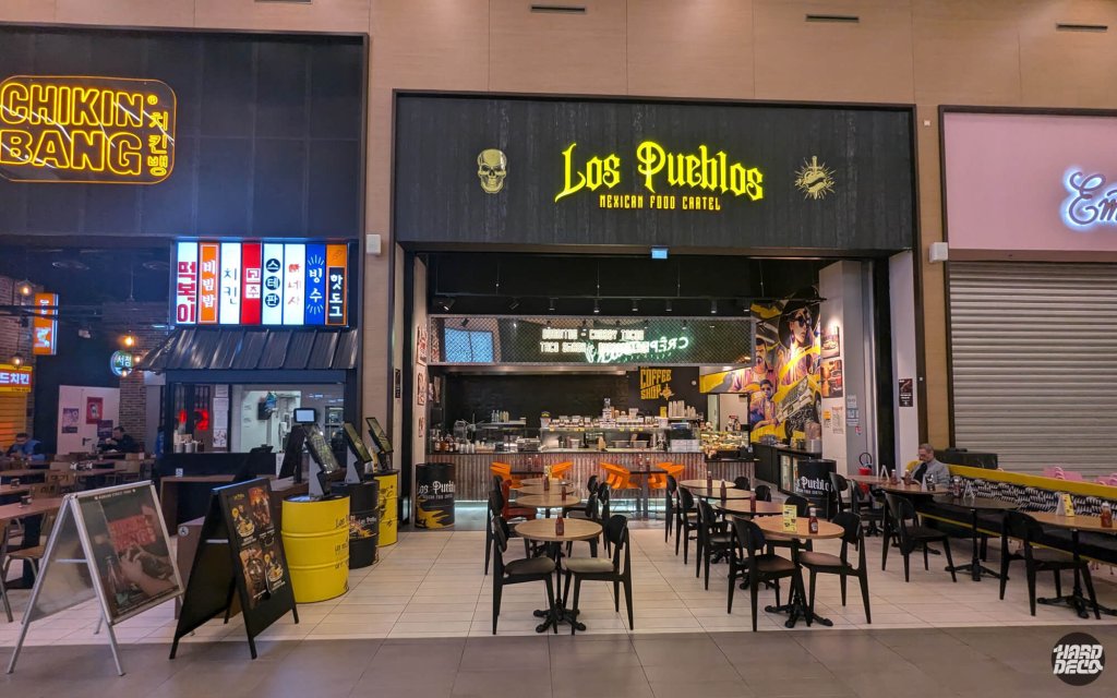 Façade du restaurant Los Pueblos Mexican Food Cartel dans un food court, fresque visible en arrière-plan