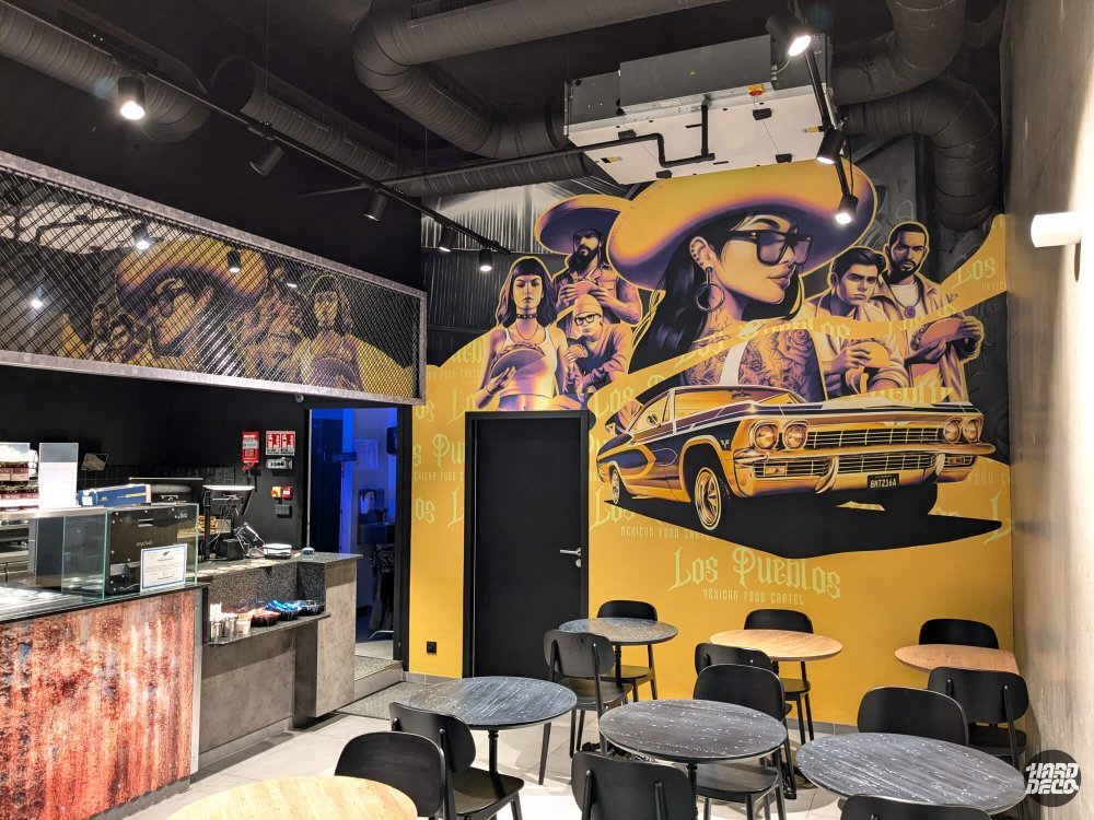 Vue intérieure du restaurant Los Pueblos Grenoble avec fresque murale chicano sur fond jaune or