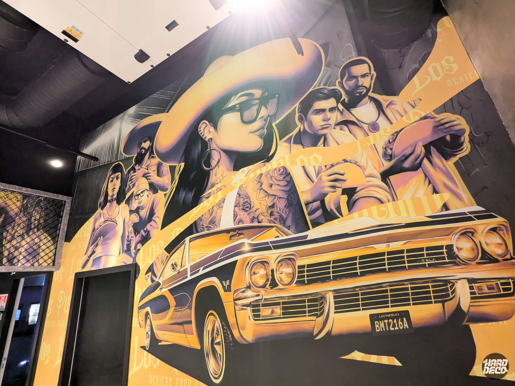 Fresque murale aérosol Los Pueblos Grenoble, lowrider Chevrolet doré et personnages chicano tattoués