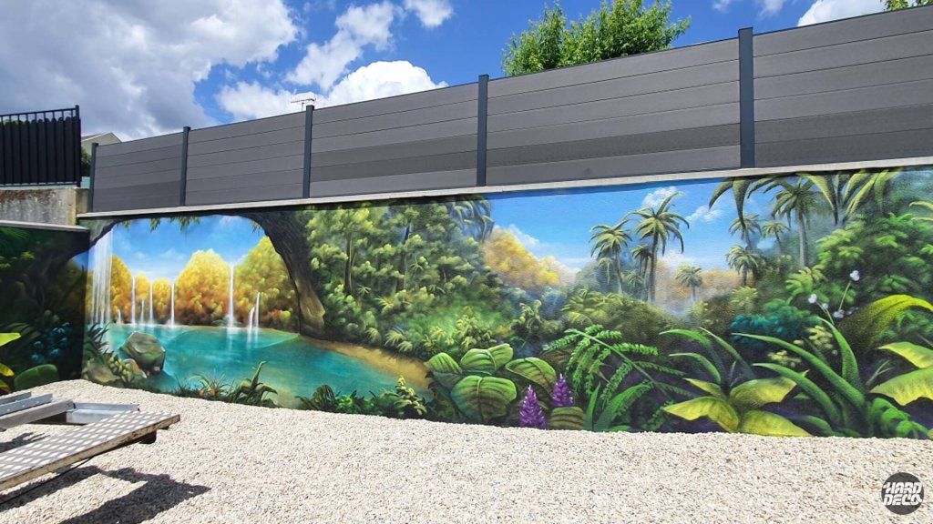 Vue d'ensemble fresque jungle tropicale aérosol sur clôture de jardin, cascades et végétation dense