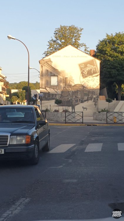 Fresque murale Livry-Gargan vue depuis la rue au soleil couchant, façade pignon avec carte postale ancienne peinte en sépia