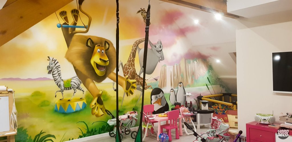 Fresque Madagascar salle de jeux : lion Alex, zèbre Marty et girafe Melman peints à l'aérosol sur mur incliné