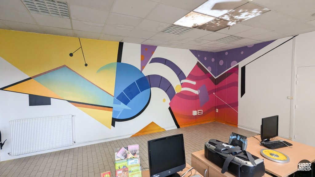Fresque murale géométrique colorée salle informatique Espace Jeunesse Montfermeil, formes abstraites jaune bleu violet rose