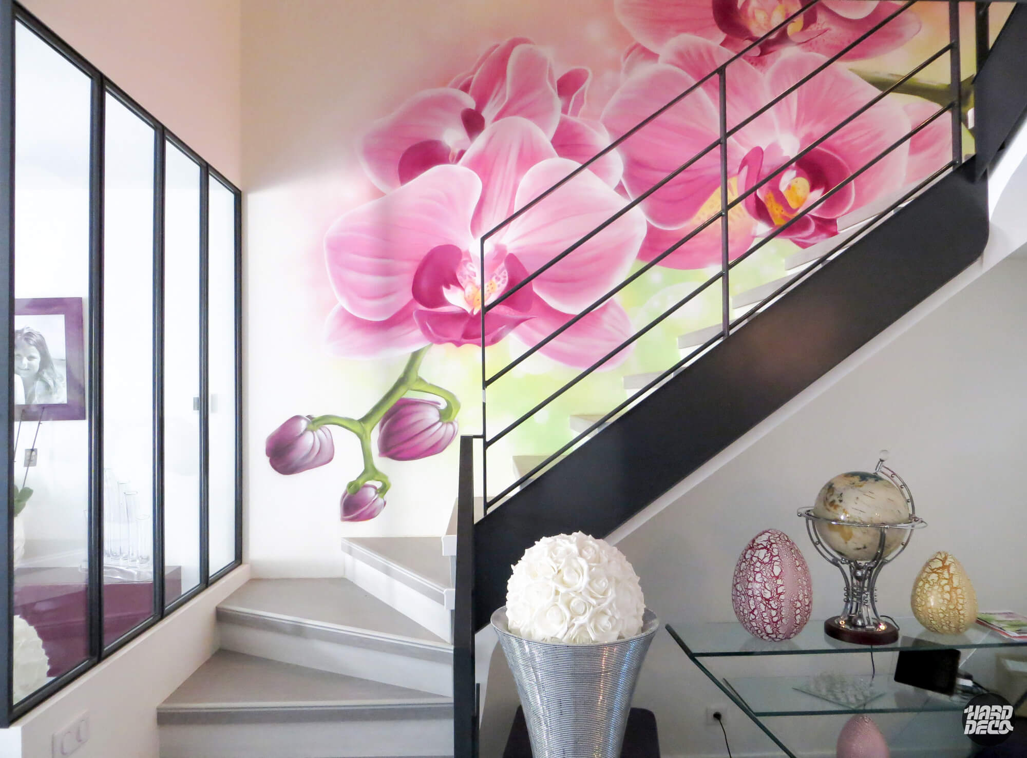 Fresque murale orchidées roses à l'aérosol dans une cage d'escalier contemporaine, rampe noire, 13 m²
